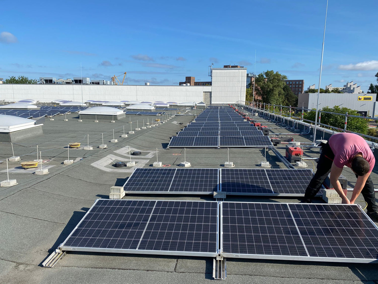 Monteur richtet Photovoltaikmodule auf einem gewerblichen Flachdach aus