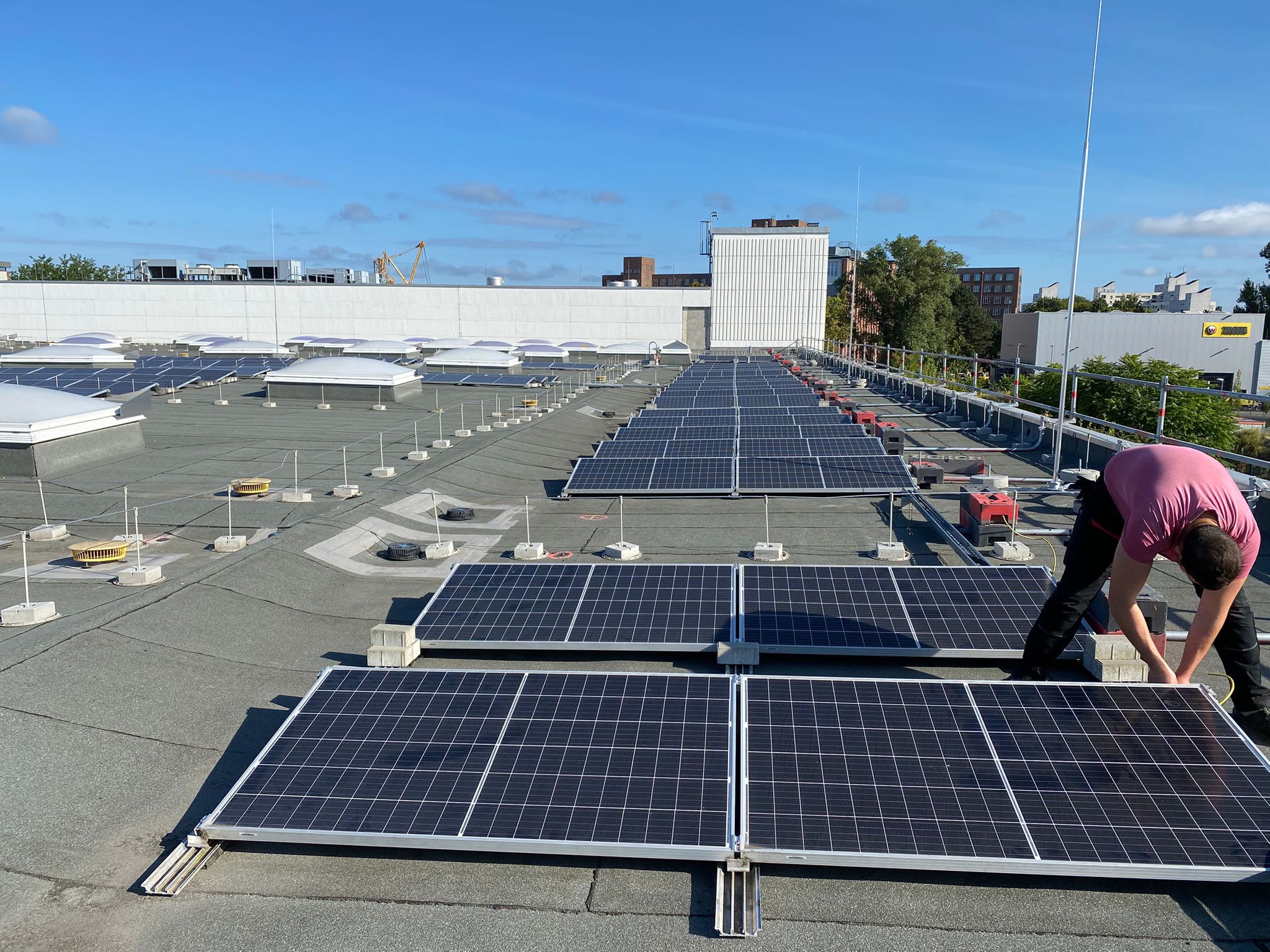 Monteur richtet Photovoltaikmodule auf einem gewerblichen Flachdach aus